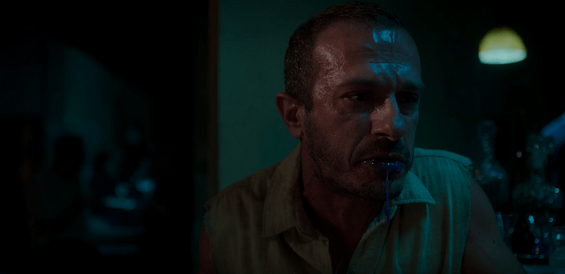 A man chokes and vomits purple ooze.